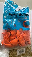Sealed pack of orange party balloons with blue and white packaging.