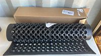 Rolled black rubber door mat laid out partially with packaging box visible.
