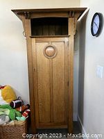 Full view of the armoire showing front door, top cornice with decorative brackets, and side hooks