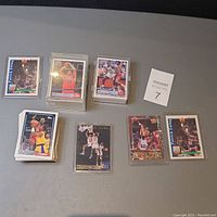 Stacks of assorted basketball trading cards from early 90s including some sleeved cards and visible player images