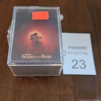 Plastic case holding complete set of Beauty and the Beast trading cards with box art showing silhouette of Beast and Belle against a red glowing background