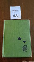 Front cover of the green hardcover book with ink spots and worn edges.