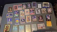 Wide view of multiple baseball cards arranged on a table showing mixed cards, some sleeved and some loose