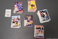 Five stacks of 1990s hockey cards arranged on a gray background, showing distinct card backs and fronts with various players.