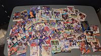 Top-down image showing a large assortment of loose hockey cards spread on a table, with visible wear on many cards