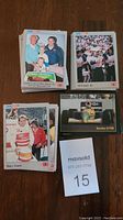 Stack of NASCAR and IndyCar trading cards showing front card with Pancho Carter and others, some cards visible with images of drivers, stacks arranged on table with MaxSold lot number sign.