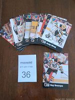 Top view of 13 1992 Pro Set PUCK hockey cards arranged fanned out on a wooden surface, showing player images and names, including Andy Moog and Ray Bourque.