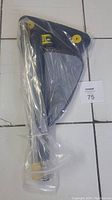 Packaged blue and gray triangular mop head with telescopic pole, sealed in plastic wrapping, against white tiled floor.