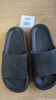 Top view of black open-toe slippers showing ribbed wide strap and textured footbed.