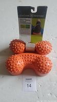 Photo of two orange Gaiam Restore Hot & Cold Neck Cradles with textured nodules and visible packaging.