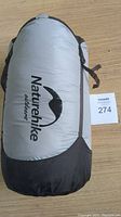 Grey and black Naturehike Outdoors sleeping bag in a compact carry sack with logo visible on side.