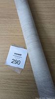 Roll of light wood grain self adhesive vinyl on a matching wood surface with lot tag visible.