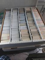 A box filled with thousands of hockey cards organized in vertical rows inside a white storage box.