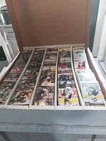 Photo shows a white box filled with approximately 4,000 hockey trading cards organized in five columns separated by dividers. Cards depict hockey players in colorful uniforms, arranged vertically and packed tightly.