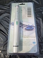White pen-style combustible gas leak detector with user controls and indicator lights, sealed on retail backing card showing a gas stove image.