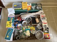 Wide view of lots of miscellaneous hardware items and the vintage metal toolbox underneath.