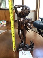 Front view of the wooden figurine next to a tape measure showing a height of about 14.5 inches.