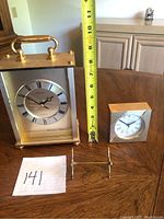 Wide view showing two clocks and knife holder with measurement tape next to larger clock showing height approx. 8 inches.