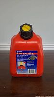 Red plastic 5 litre (1 1/4 gallon) self venting fuel can with screw cap, shown front facing with label visible.