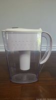 Side view of transparent Brita water pitcher showing the white filter cartridge inside and the handle.
