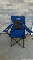Front view of the blue Coleman camping chair showing the black mesh back, armrests with a cup holder on the right side, and foldable black metal frame.