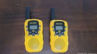 Front view of two yellow DILISS walkie talkies showing LCD screen, buttons, speaker and antenna
