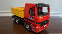 Side view of the Bruder Mercedes Actros toy truck showing the red cab, yellow cargo bed, and detailed wheels.