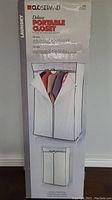 Photo of packaging box featuring image of white zippered fabric portable closet on metal frame with clothes hanging inside