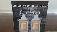 Box showing the LED Lantern Set with 2 lanterns, Model LP8900W, against a dark brick wall background.