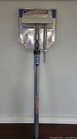 Full view of StainStick stain spreading tool in original packaging, mounted on wall.