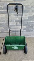 Front view of green Scotts AccuGreen 1000 fertilizer spreader with handle and wheels.