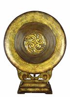 Front-facing photo of a bronze style metal platter on a wooden decorative stand. Shows detailed texture and design on the platter and the carved scroll cut-out on the stand.