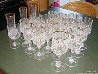 Photo showing full set of 20 glasses on wooden kitchen surface, highlighting faceted crystal and gold rims.