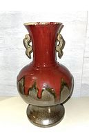Front view of the glazed pottery vase showing red upper shading with greenish drips and brown mottled base, plus sculpted handles.