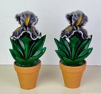 Front view of the pair of purple flower wax candles in terracotta clay pots, showing both items side by side.