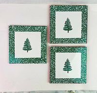 Three square ceramic Christmas tree tiles arranged showing their front designs, with green textured borders and central Christmas tree motifs on white background.