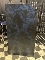 Photo showing the blue faux marble styled panel with gold trim and curved corner edge against a black and white checkered floor.