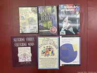 Five books and one DVD arranged on a wooden surface, showing front cover art and titles.