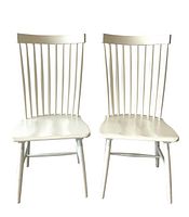 Front view of two white spindle farmhouse dining chairs showing vertical spindle back design and seat shape.