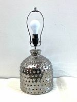 Front view of the faceted silver metal lamp base with visible bulb socket and harp, on a plain background.