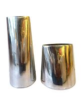 Photo of two modern stainless steel polished silver metal vases. One taller, more slender vase on left, one shorter, wider vase on right.