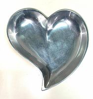 Heart-shaped catchall tray made of silver pewter with a reflective surface.
