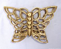 Front view of vintage brass butterfly napkin holder showing detailed openwork wings and body.