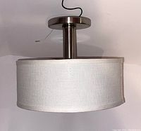 Side view of white linen flush ceiling pendant light showing drum shade and metal fixture.