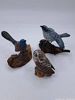 Three hand painted bird figurines including one owl on wood bases, arranged together showing detail and size difference.