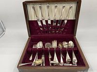 Full view of Birks flatware set inside wooden canteen lined with burgundy velvet and satin.