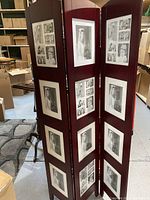 Three-panel wooden standing photo frame showing vintage black and white photographs in white mats, placed in a storage setting.