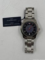 Full view of the Tommy Hilfiger wristwatch showing the stainless steel bracelet and attached tag.