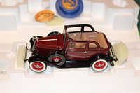 Maroon and black 1932 Ford V-8 model car inside foam packaging showing detailed exterior, wheels, interior, and working parts.