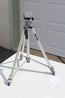 Full view of the SLIK Insta-Lok 800G-FL lightweight tripod standing on a white surface outside a garage door.